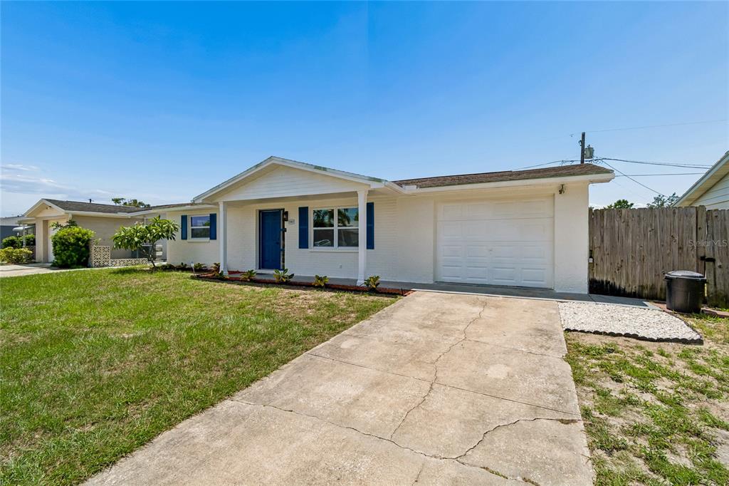 A single-story white house with a blue front door and a concrete driveway — 1467 CLASSIC DRIVE, HOLIDAY, FL
