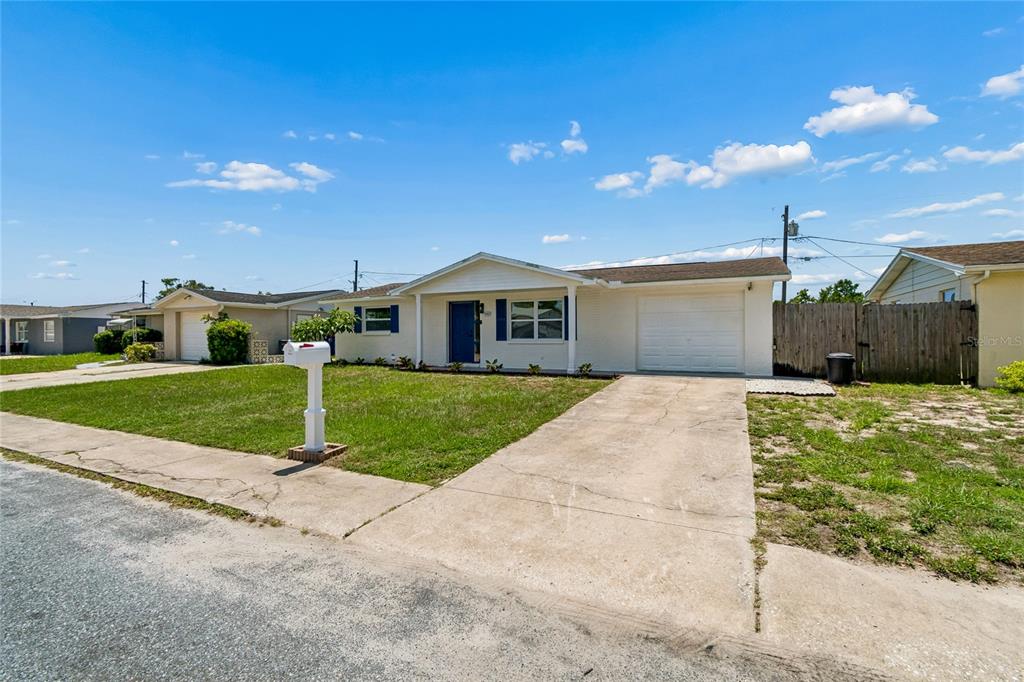 A single-story house with a white exterior, a blue front door, and a concrete driveway — 1467 CLASSIC DRIVE, HOLIDAY, FL