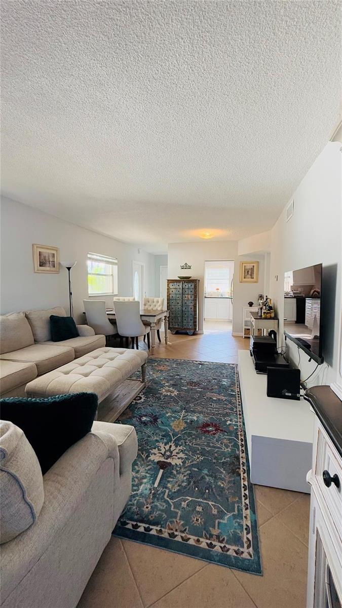 A living room with a beige sectional, a patterned area rug, and a dining area — 4200 Crystal Lake Drive # 210, Pompano Beach FL 33064, POMPANO BEACH, FL