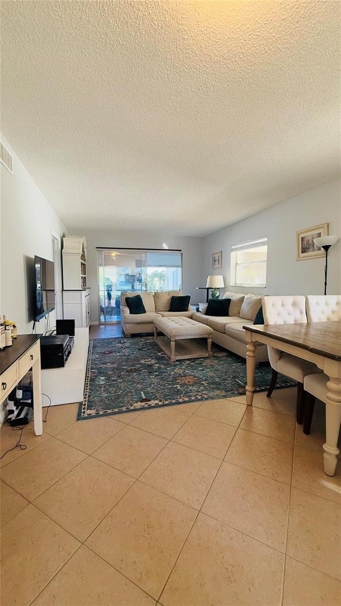 A living room with tile floors, a large area rug, and a sectional sofa — 4200 Crystal Lake Drive # 210, Pompano Beach FL 33064, POMPANO BEACH, FL