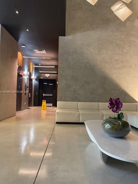 A modern lobby features a white sofa, a coffee table with flowers, and polished floors — 151 SE 1ST # 1503, Miami FL 33131, MIAMI, FL