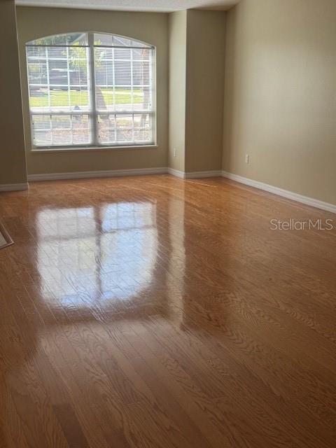 An empty room with light-colored walls, hardwood flooring, and a large arched window — 6741 NORTHLAKE DRIVE, ZEPHYRHILLS, FL