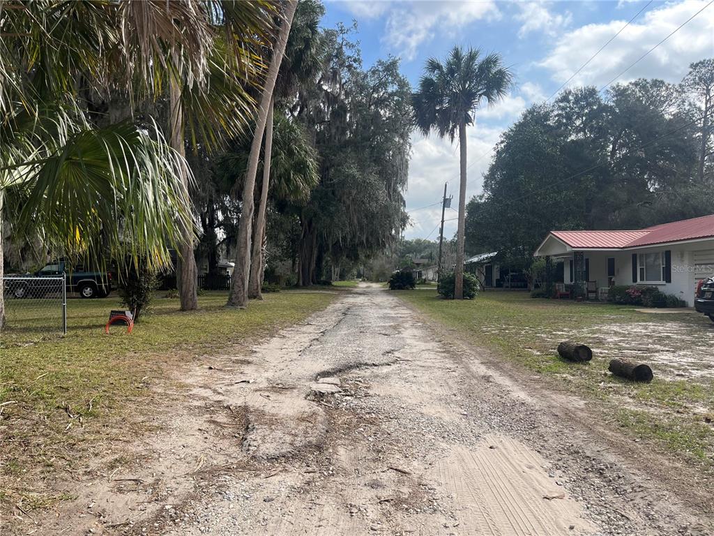 A dirt road leads through a residential area with trees and houses on both sides — 183RD AVENUE, HAWTHORNE, FL