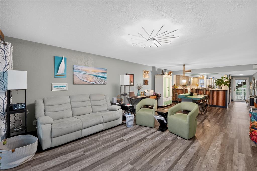 A living room with gray walls, wood-look flooring, a light gray sofa, and two chairs — 1960 OREGON TRAIL UNIT 2B, ENGLEWOOD, FL