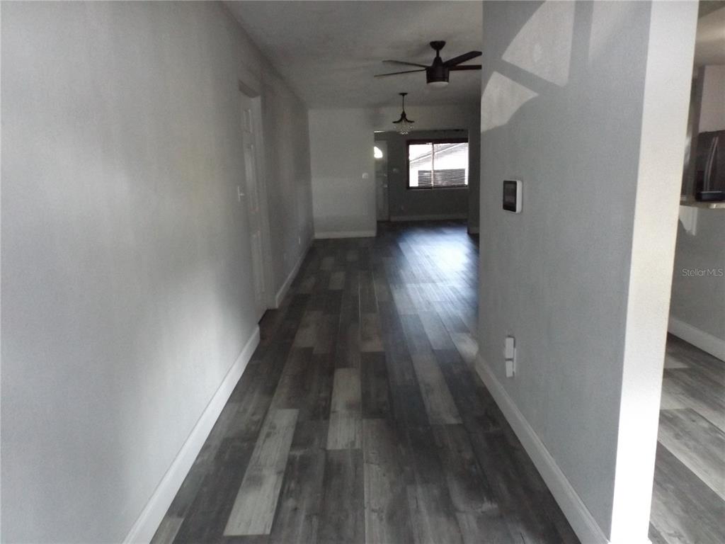 A hallway with gray wood-look flooring leads toward a room with a window — 199 8TH STREET SE, WINTER HAVEN, FL