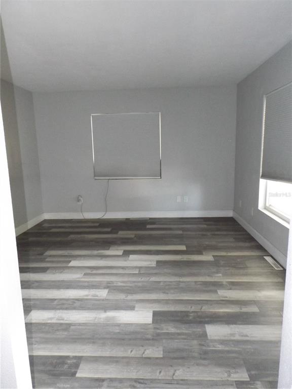 An empty room with gray walls, wood-look plank flooring, and two windows with blinds — 199 8TH STREET SE, WINTER HAVEN, FL