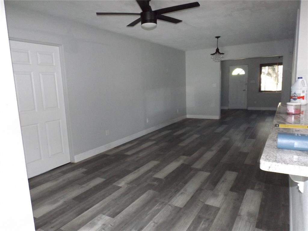 An interior view shows a living area with gray wood-look flooring and a ceiling fan — 199 8TH STREET SE, WINTER HAVEN, FL