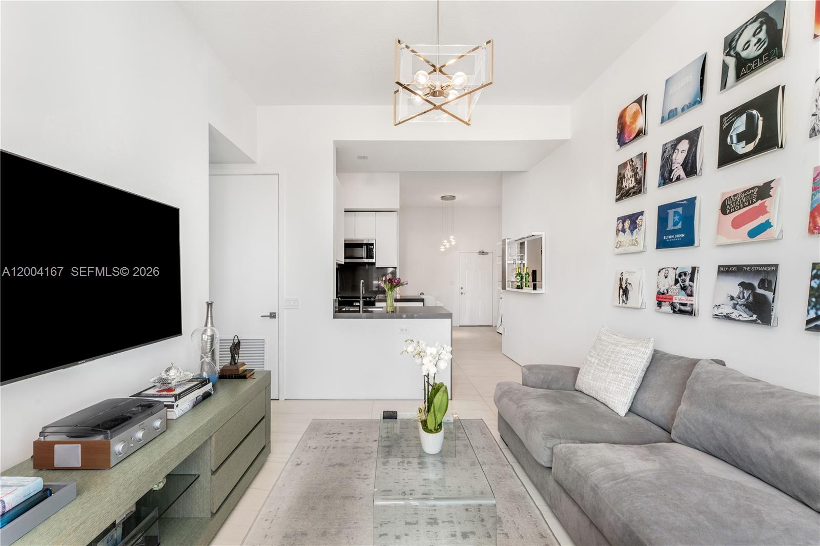 A living room features a gray sofa, a glass coffee table, and vinyl records displayed on the wall — 1723 SW 2nd Ave, Miami FL 33129, MIAMI, FL