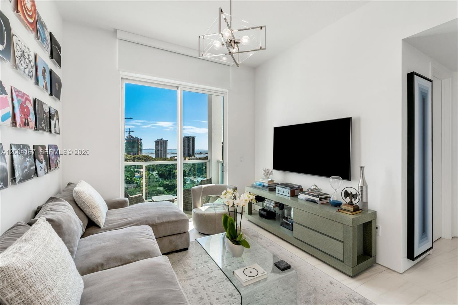 A modern living room features a grey sectional sofa, glass coffee table, and balcony view — 1723 SW 2nd Ave, Miami FL 33129, MIAMI, FL