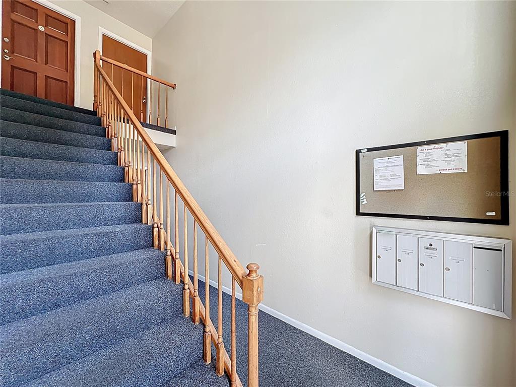 A carpeted staircase with a wooden railing leads to a landing with mailboxes and a bulletin — 4212 LAKE UNDERHILL ROAD UNIT 5D11, ORLANDO, FL