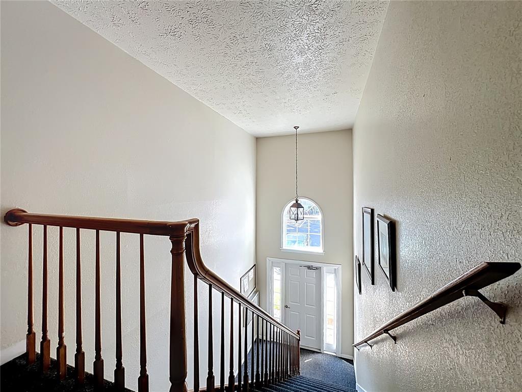 A staircase with a wooden railing leads down to an entryway with a front door — 4212 LAKE UNDERHILL ROAD UNIT 5D11, ORLANDO, FL