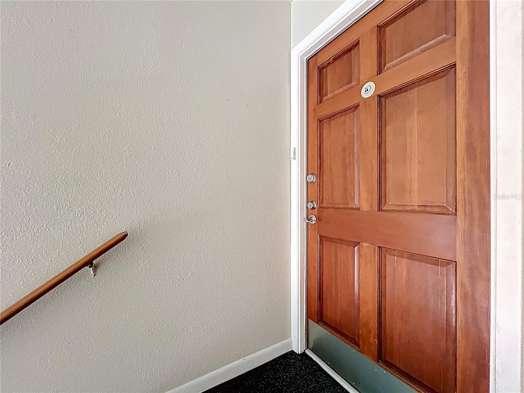 A wooden door with a metal kickplate is positioned next to a wall-mounted handrail — 4212 LAKE UNDERHILL ROAD UNIT 5D11, ORLANDO, FL