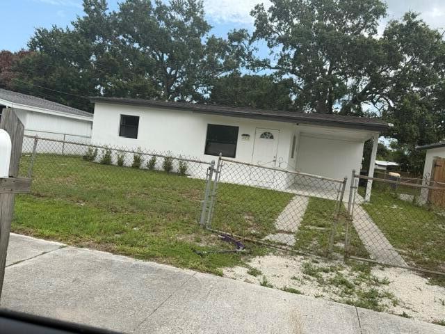 A single-story white house with a dark roof and a chain-link fenced front yard — 2002 Avenue P, Fort Pierce FL 34950, FORT PIERCE, FL