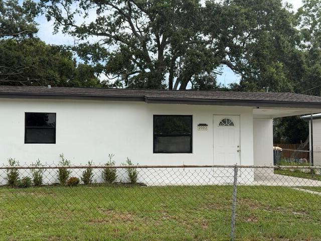 A single-story white house with a dark roof and a chain-link fence in front — 2002 Avenue P, Fort Pierce FL 34950, FORT PIERCE, FL