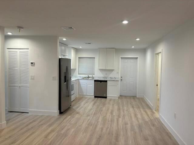 A kitchen features white cabinets, stainless steel appliances, and light wood-look flooring — 2002 Avenue P, Fort Pierce FL 34950, FORT PIERCE, FL