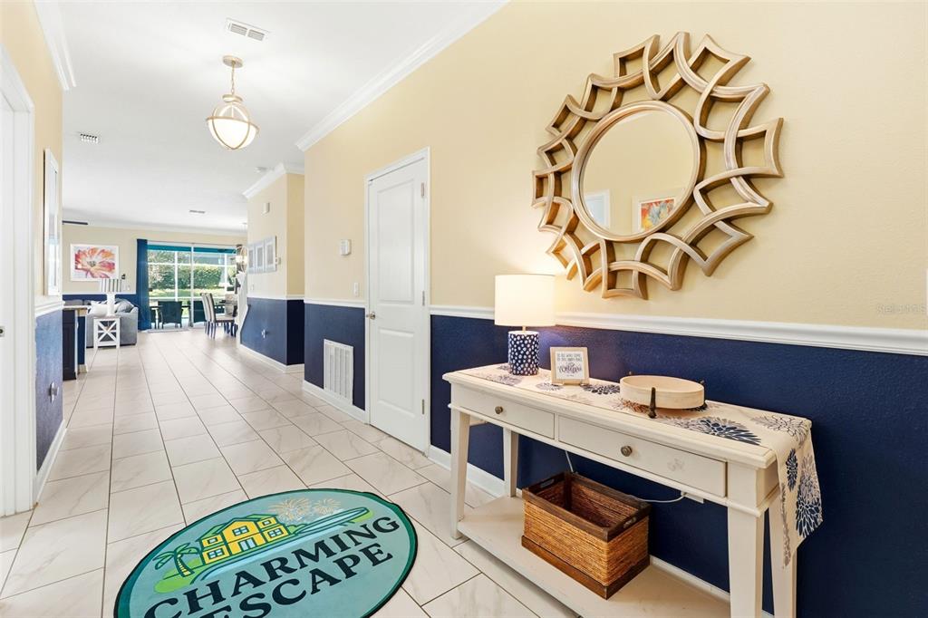 An entryway features a console table, a decorative mirror, and a blue and cream wall — 9099 HAZARD STREET, DAVENPORT, FL