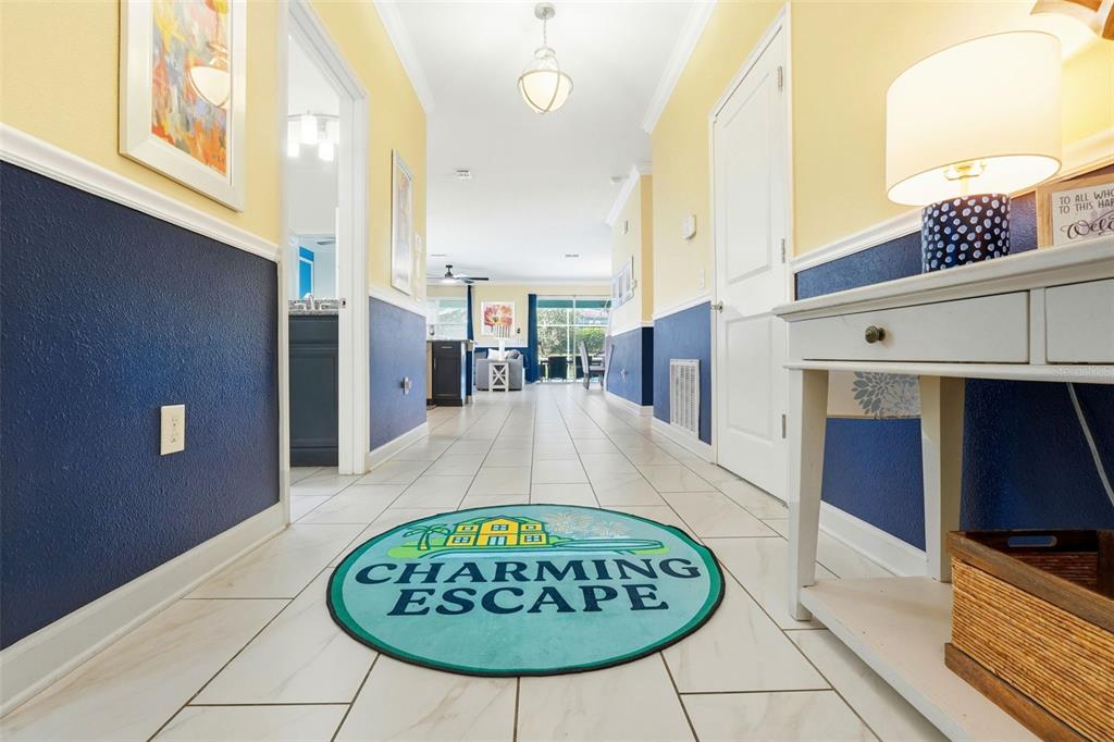 A hallway with tile floors, blue and yellow walls, and a circular welcome rug — 9099 HAZARD STREET, DAVENPORT, FL