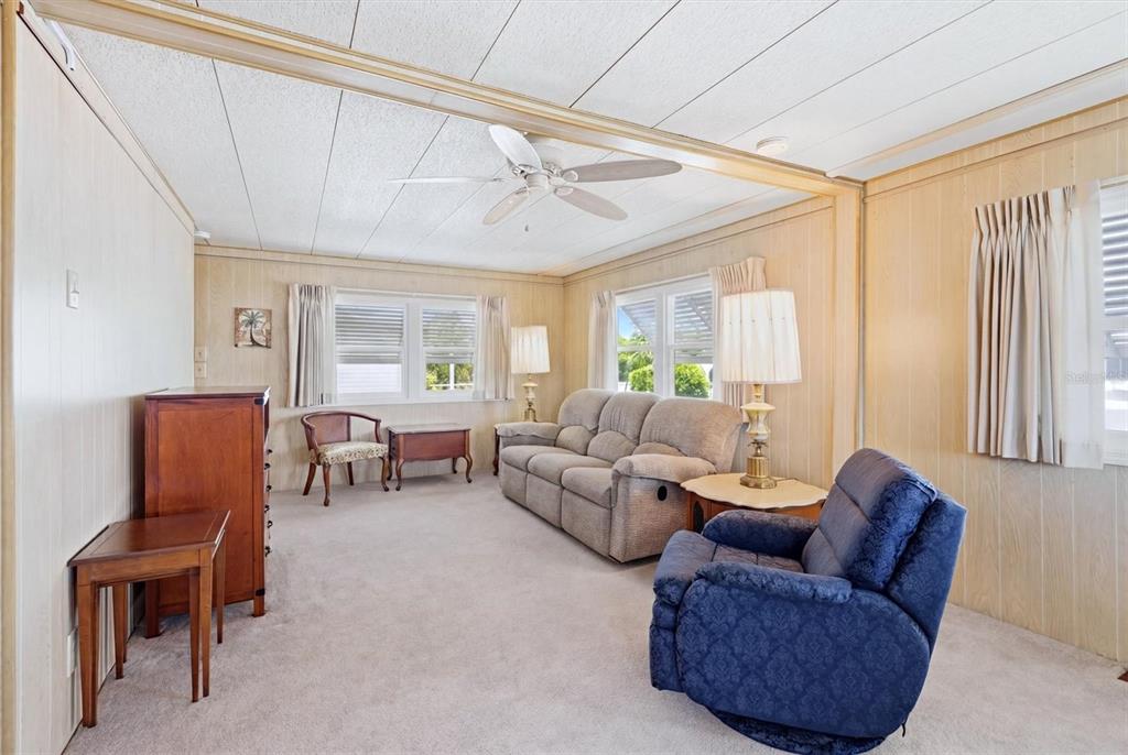 A living room features wood-paneled walls, a beige sofa, a blue recliner, and carpeted floors — 4203 11TH STREET COURT E, ELLENTON, FL