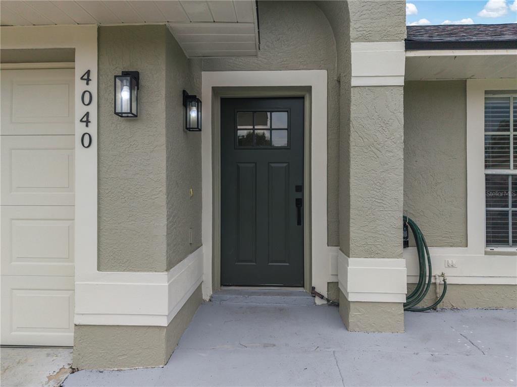 A tiled entryway leads to a living room with a sofa and a front door — 4040 EAGLE FEATHER DRIVE, ORLANDO, FL