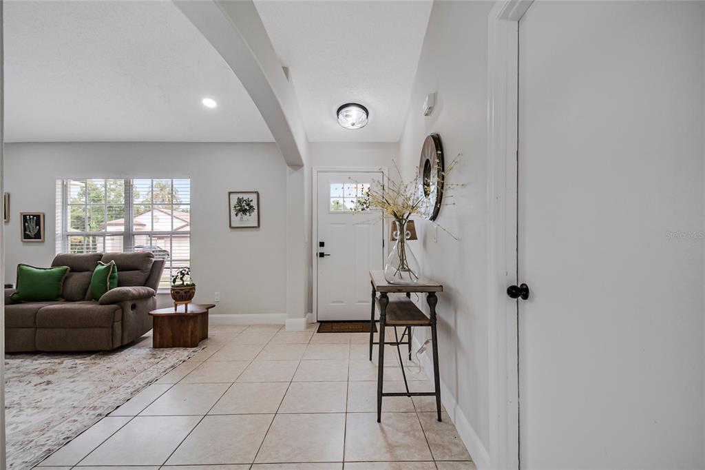 An entryway features a white front door with a window, tile flooring, and a side table — 4040 EAGLE FEATHER DRIVE, ORLANDO, FL
