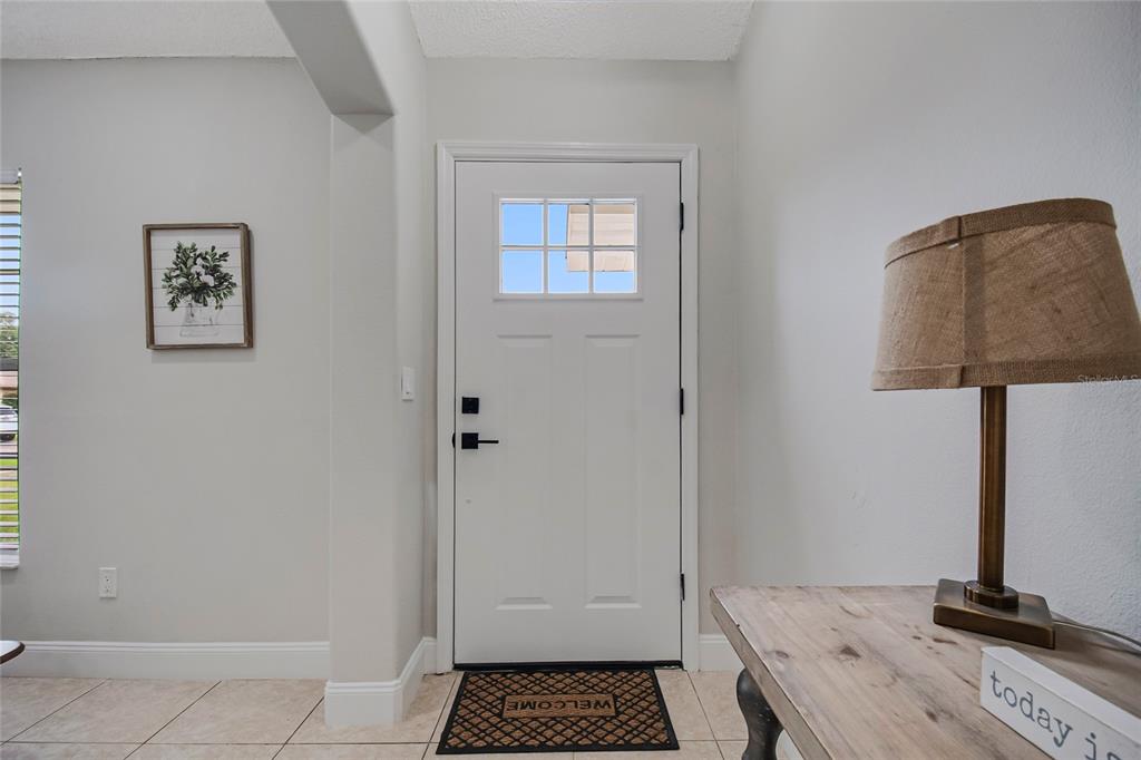 A modern kitchen features white cabinets, quartz countertops, a breakfast bar, and three woven stools — 4040 EAGLE FEATHER DRIVE, ORLANDO, FL