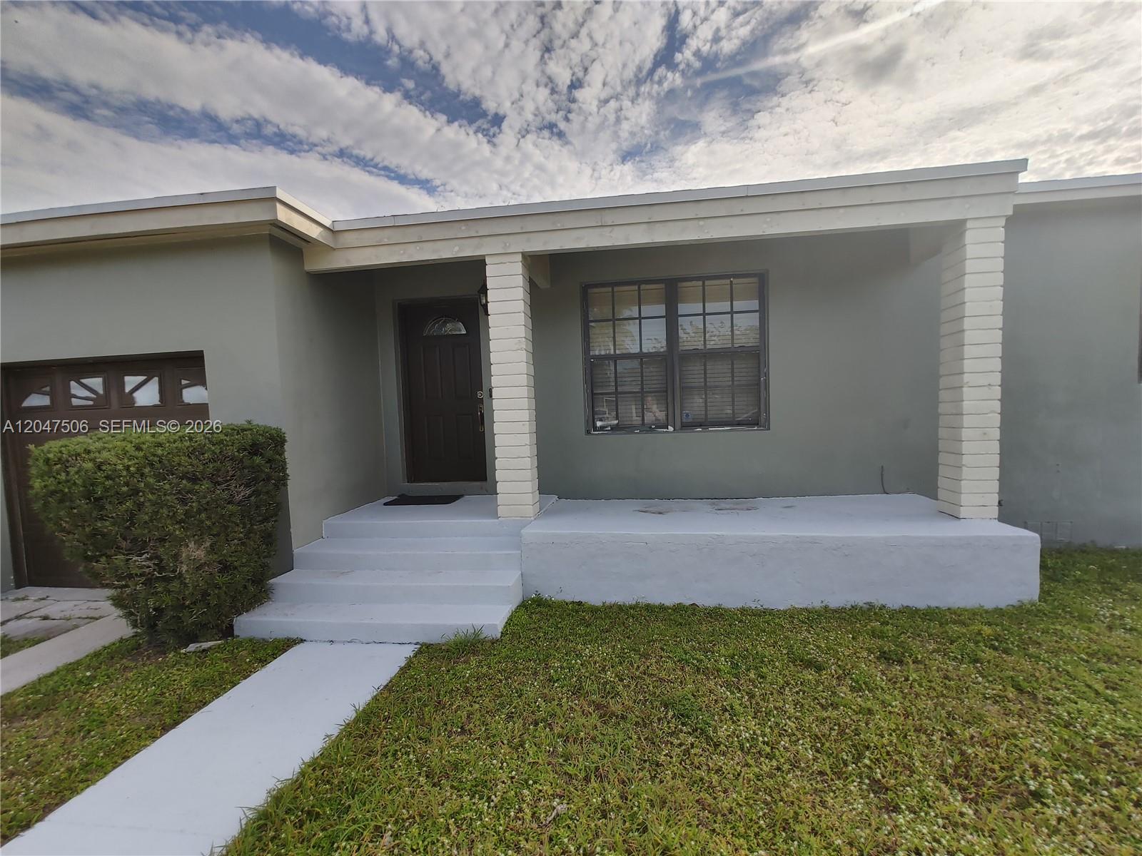 A gray house exterior features a covered porch, white brick columns, and a front door — 14901 NW 9th Ct # 14901, Miami FL 33168, MIAMI, FL