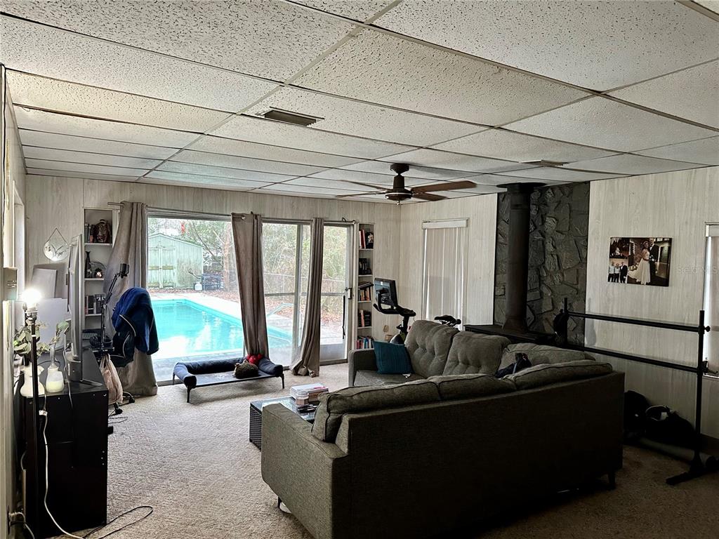 A living room features a drop ceiling, stone fireplace, sectional sofa, and sliding glass doors — 424 W HOGLE AVENUE, DELAND, FL