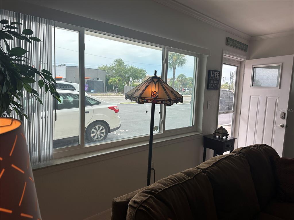 A living room features a large window, a stained-glass floor lamp, and a front door — 6161 GULF WINDS DRIVE UNIT 150, ST PETE BEACH, FL