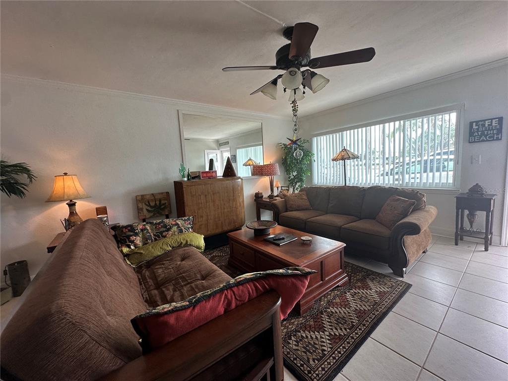 A living room features two brown sofas, a wooden coffee table, and a ceiling fan — 6161 GULF WINDS DRIVE UNIT 150, ST PETE BEACH, FL