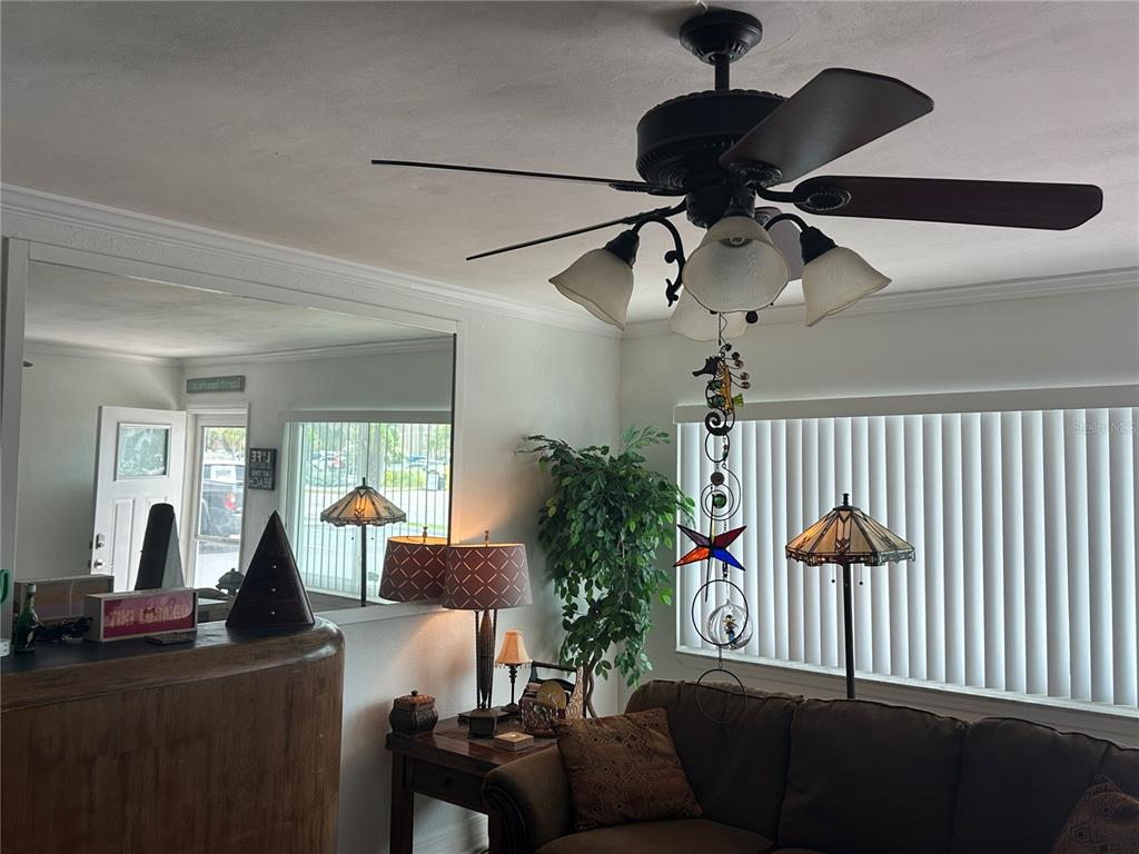 A living room features a ceiling fan, a large wall mirror, and a brown sofa — 6161 GULF WINDS DRIVE UNIT 150, ST PETE BEACH, FL
