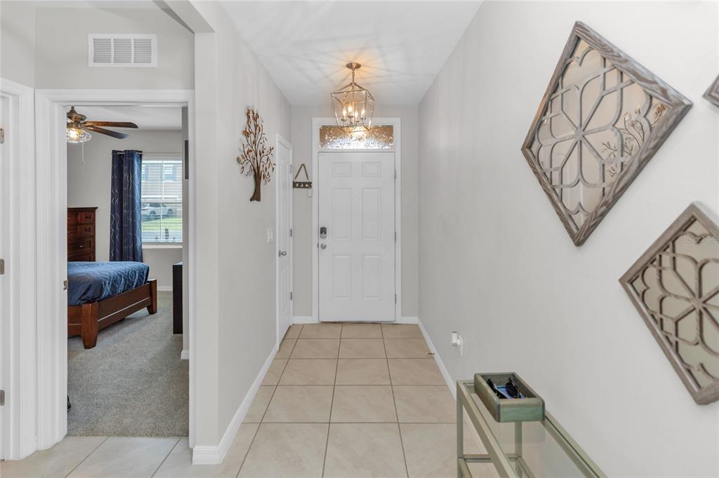A tiled entryway features a white front door, a hanging lantern light, and wall decor — 839 LAZIO CIRCLE, DEBARY, FL