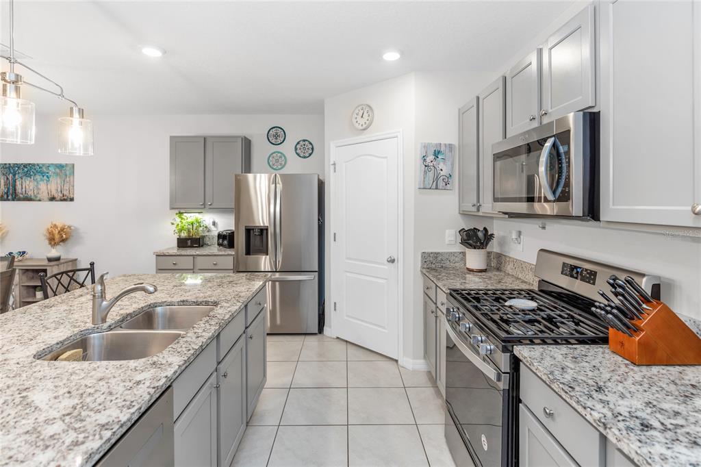 A kitchen features gray cabinets, granite countertops, stainless steel appliances, and a central island — 839 LAZIO CIRCLE, DEBARY, FL