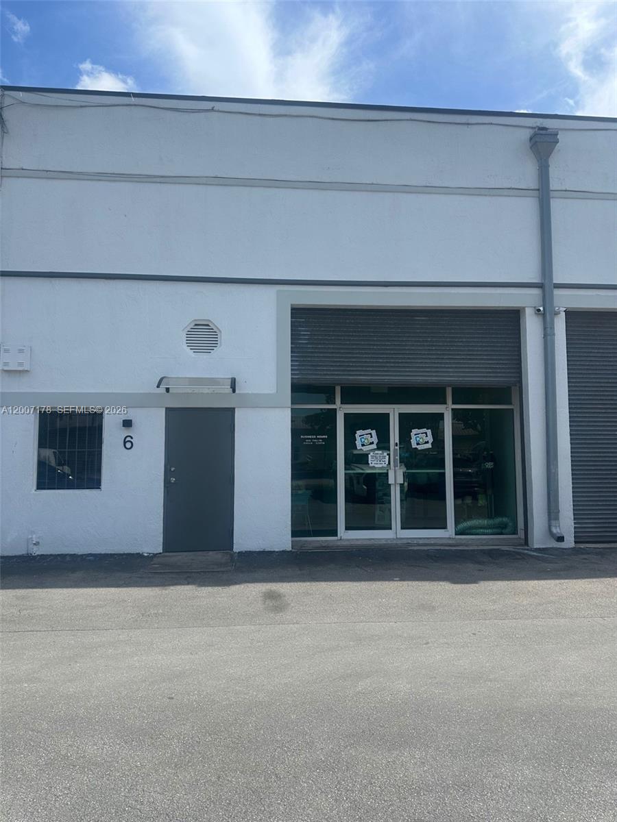 The exterior of a commercial building features a gray door labeled six and glass entrance doors — 12101 NW 98th Ave, Hialeah Gardens FL 33018, HIALEAH GARDENS, FL