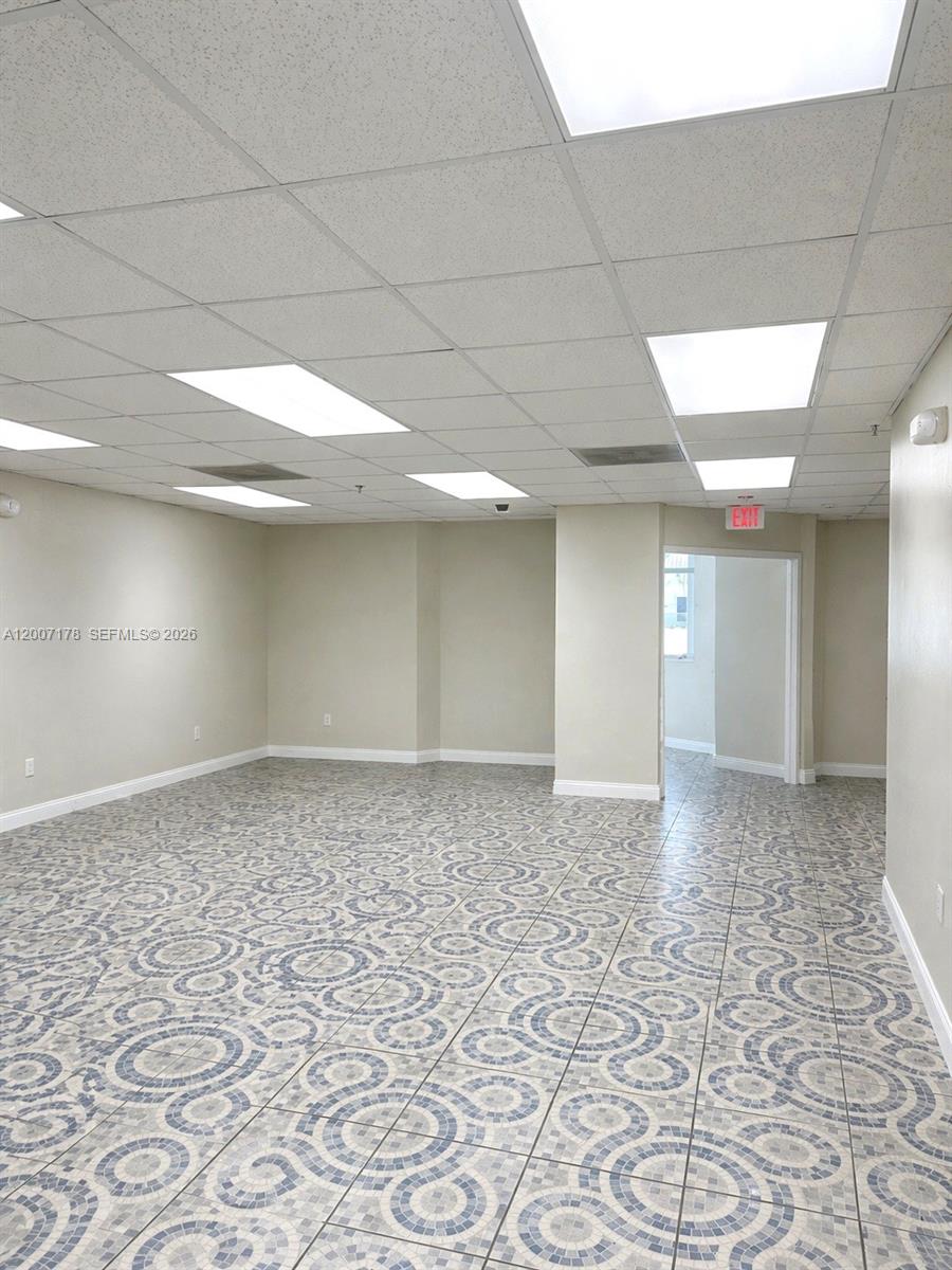 An empty office space features a patterned tile floor and a drop ceiling with lights — 12101 NW 98th Ave, Hialeah Gardens FL 33018, HIALEAH GARDENS, FL