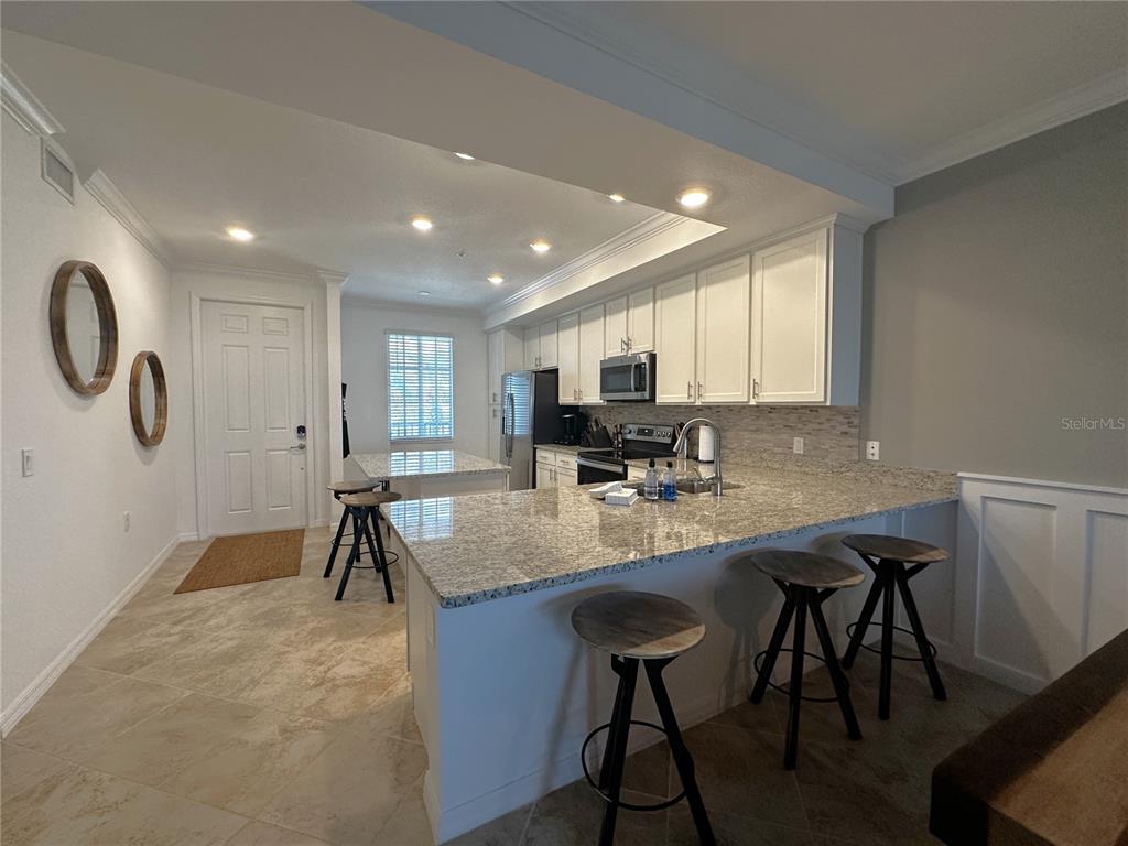 A kitchen features granite countertops, white cabinetry, stainless steel appliances, and a breakfast bar — 14091 HERITAGE LANDING BOULEVARD UNIT 134, PUNTA GORDA, FL