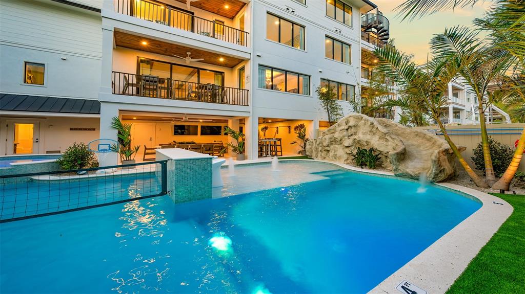 A multi-story house features a swimming pool with a rock slide and a volleyball net — 1142 WINDSONG LANE UNIT B, SARASOTA, FL