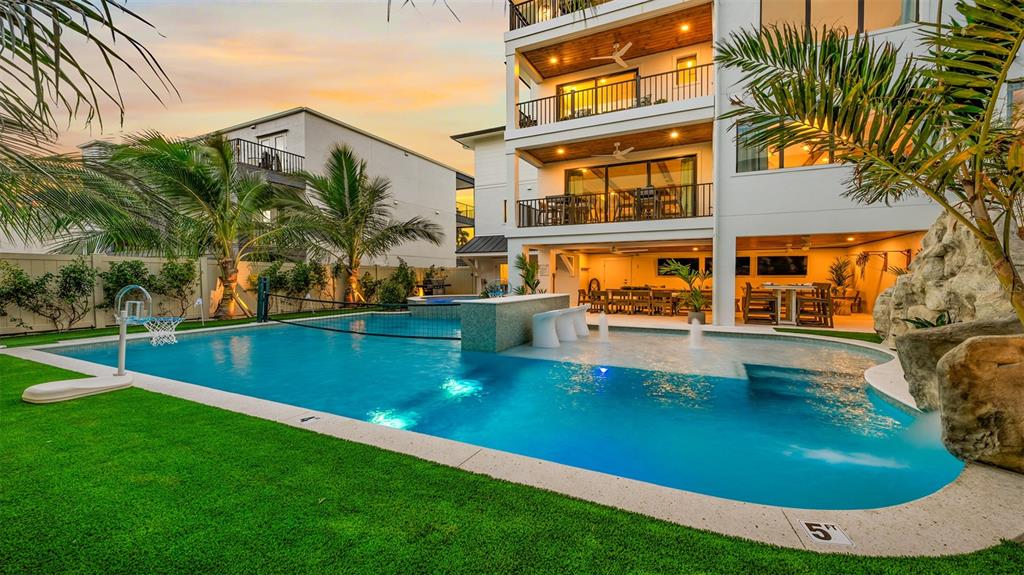 A multi-story house with a swimming pool, volleyball net, and artificial turf lawn at sunset — 1142 WINDSONG LANE UNIT B, SARASOTA, FL