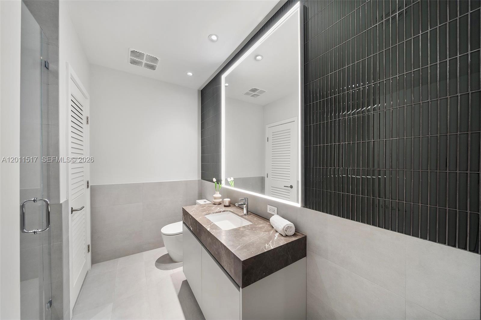 A modern bathroom features a floating vanity with a marble countertop and a backlit mirror — 500 Alton Rd # 501, Miami Beach FL 33139, MIAMI BEACH, FL