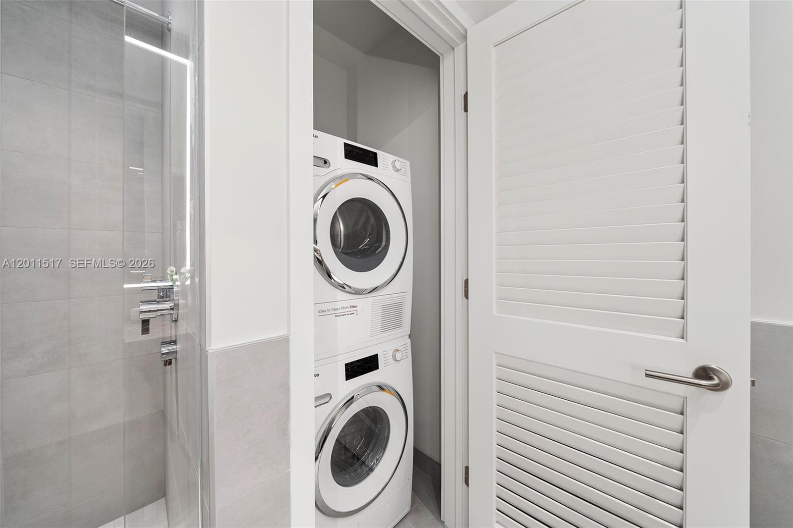 A stacked washer and dryer unit is located in a closet next to a shower — 500 Alton Rd # 501, Miami Beach FL 33139, MIAMI BEACH, FL