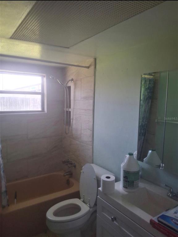 A bathroom features a beige bathtub with tiled walls, a toilet, and a white vanity — 4601 EASTWOOD LANE, HOLIDAY, FL