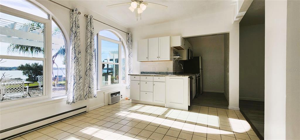 A kitchen with white cabinets and tile flooring overlooks a lake through large arched windows — 1854 HIGHLAND PARK DRIVE S UNIT A-F, LAKE WALES, FL