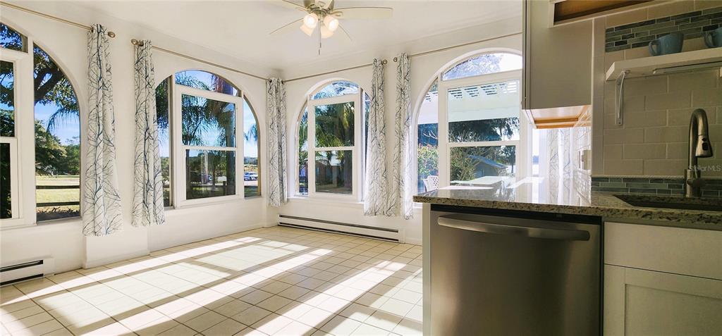 A sunroom with tile flooring, arched windows, and a partial view of a kitchen counter — 1854 HIGHLAND PARK DRIVE S UNIT A-F, LAKE WALES, FL