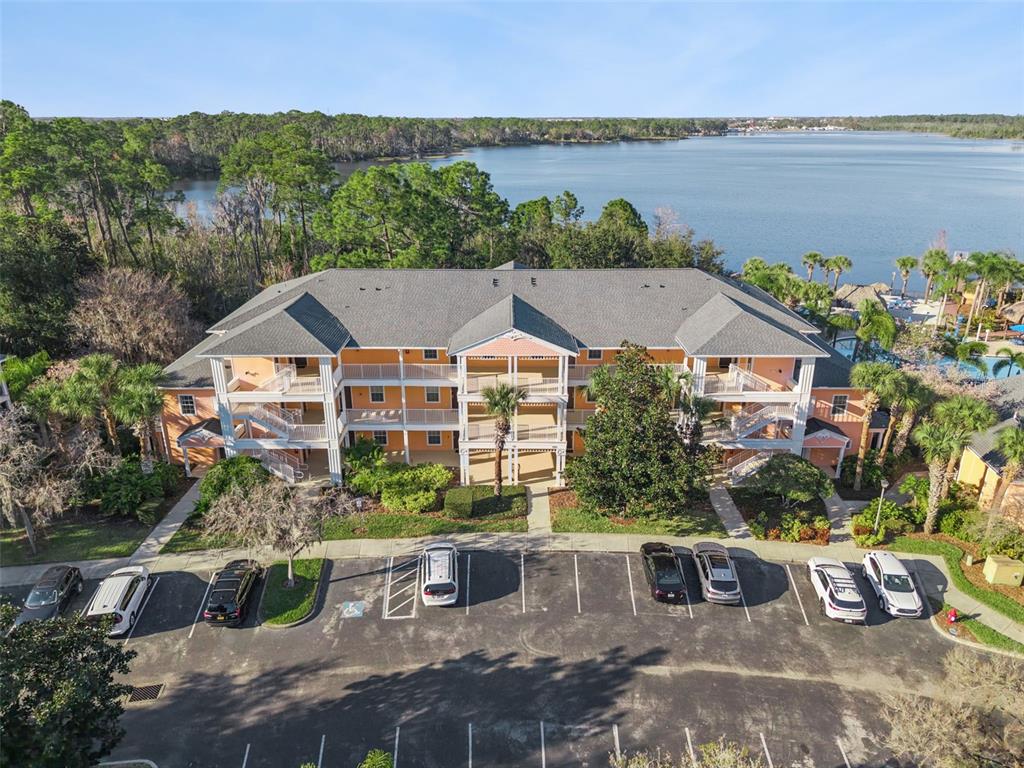 An aerial view shows a three-story apartment building with a parking lot and a lake — 714 NEW PROVIDENCE PROMENADE, DAVENPORT, FL