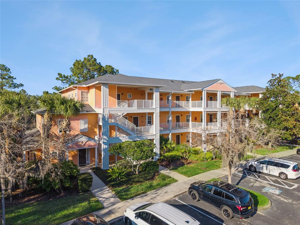 A three-story apartment building with orange siding, white railings, and an outdoor staircase — 714 NEW PROVIDENCE PROMENADE, DAVENPORT, FL