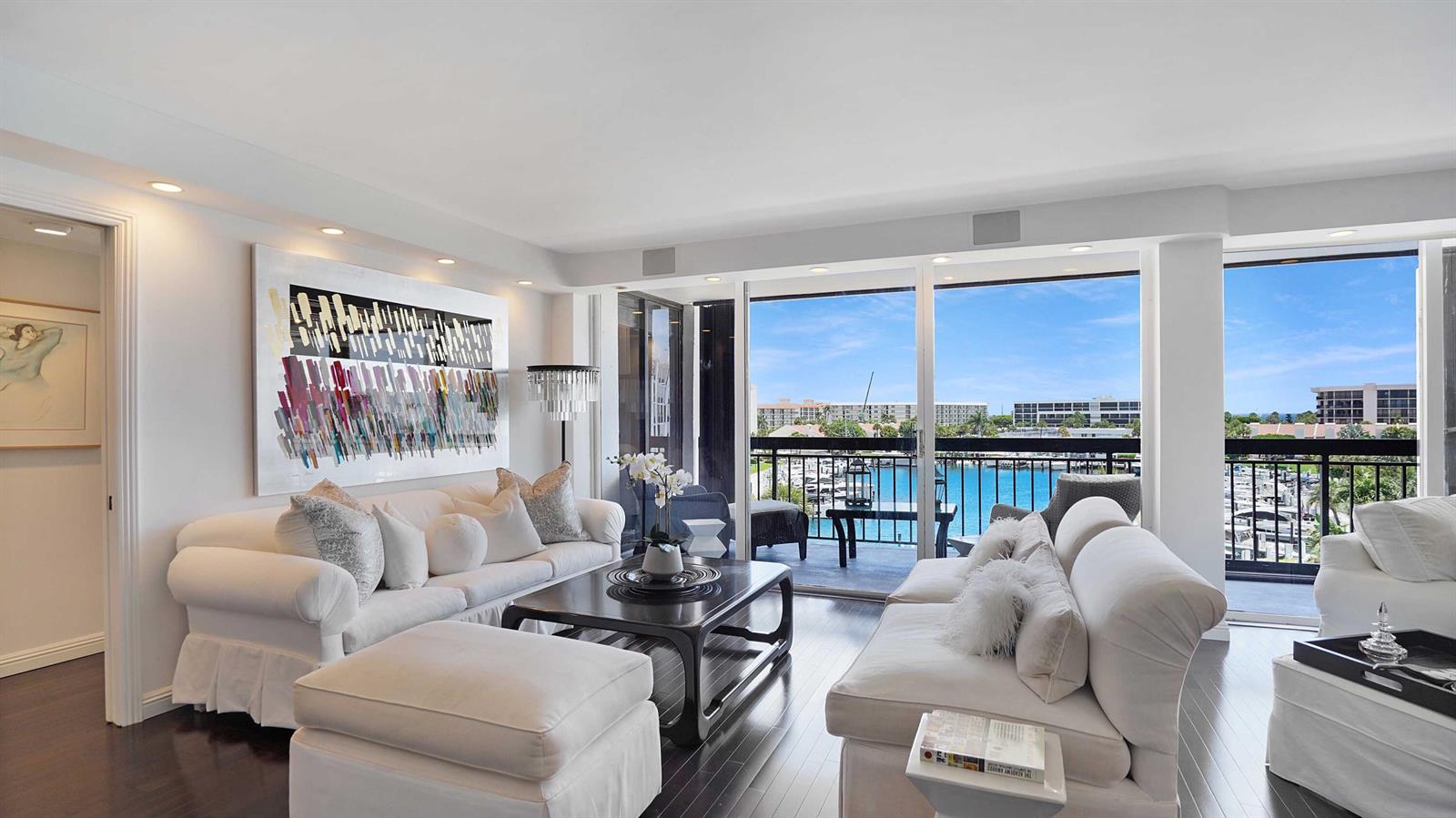 A living room with white sofas, a dark wood coffee table, and a balcony view — 2697 N Ocean Boulevard # 505, Boca Raton FL 33431, BOCA RATON, FL