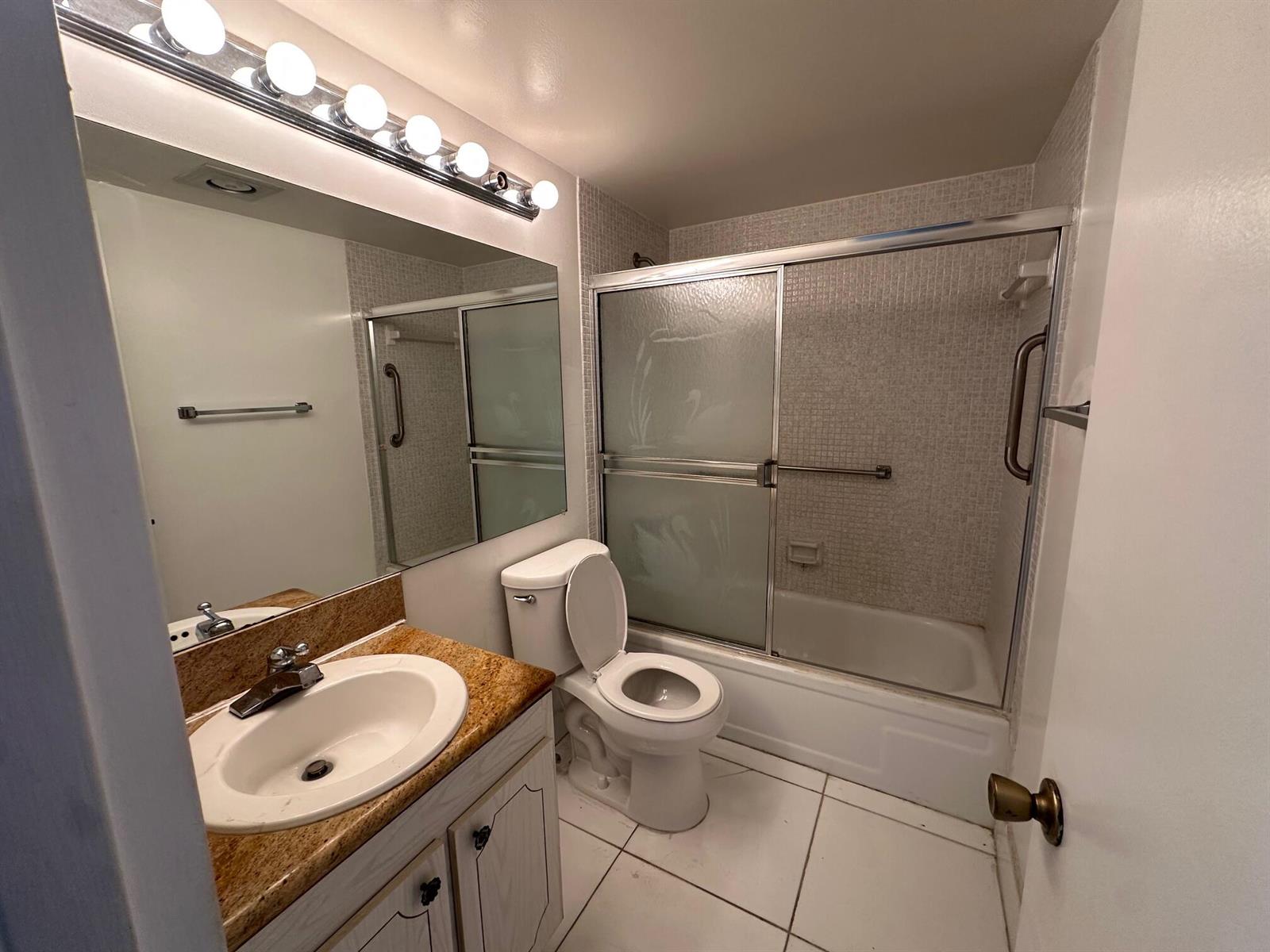 A bathroom features a vanity with a granite countertop, a toilet, and a shower-tub combo — 119 Dorset # 119, Boca Raton FL 33434, BOCA RATON, FL
