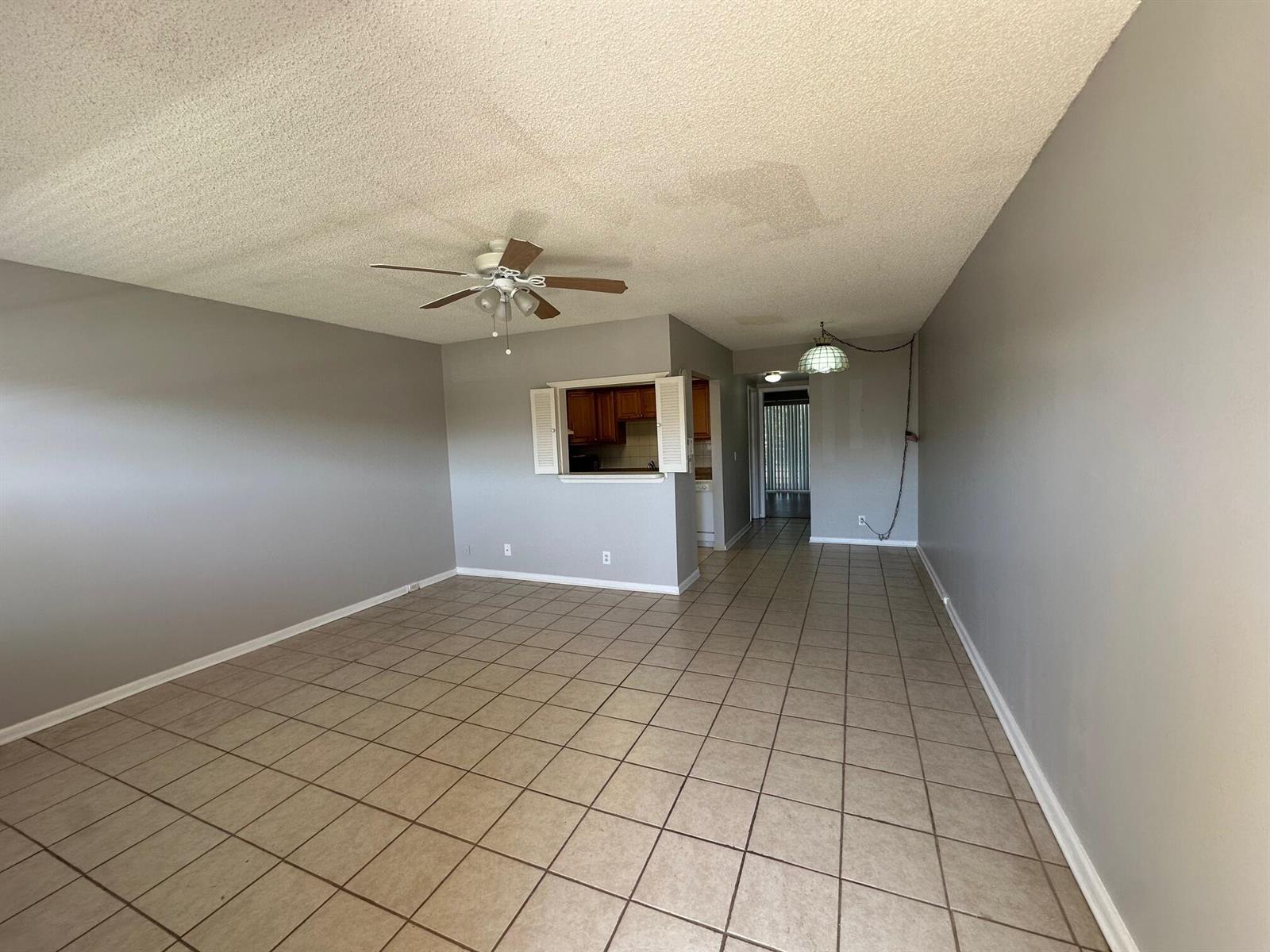 An open-concept living area features gray walls, tile flooring, a ceiling fan, and a pass-through — 119 Dorset # 119, Boca Raton FL 33434, BOCA RATON, FL
