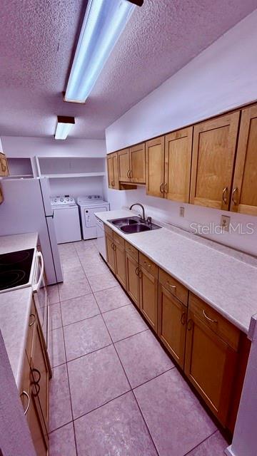 A kitchen with light wood cabinets, white countertops, tile flooring, and an adjacent laundry area — 6519 W NEWBERRY ROAD UNIT 912, GAINESVILLE, FL