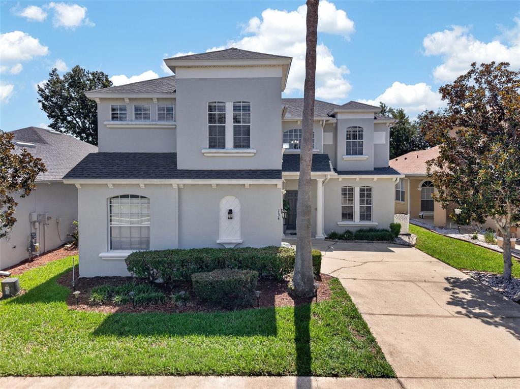 A two-story house with a light gray exterior, a concrete driveway, and a palm tree — 134 MINNIEHAHA CIRCLE, HAINES CITY, FL