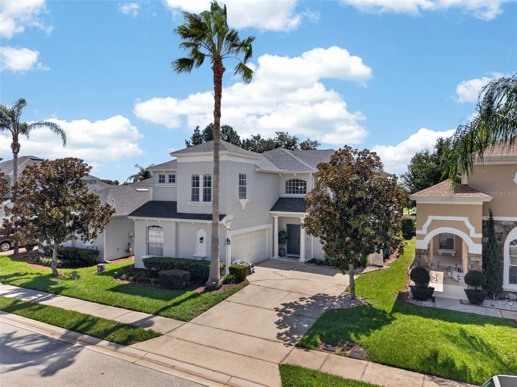 An aerial view of a two-story light gray house with a driveway and palm tree — 134 MINNIEHAHA CIRCLE, HAINES CITY, FL